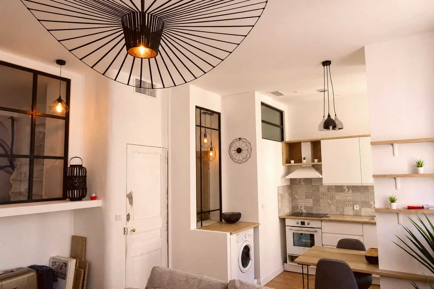 Appartement Sainte-Cécile livré : verrière noire, suspensions et cuisine claire.